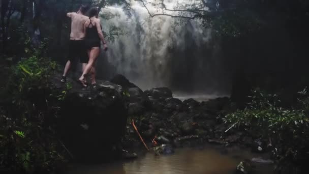 Szerelmes pár alatt egy vízesés egy barlangban. Egy pár szerelmesek. Bali kirándulás. Trópusokon. Utazás. Légi felvétel. Utazási koncepció. — Stock videók