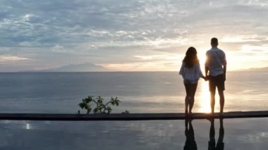 Romantik yaz tatilinde lüks tatil beldesinde aşık çift. İnsanlar Edge Yüzme Havuzu birlikte rahatlatıcı , Güzel günbatımı Deniz Manzarası Zevk. Balayı seyahatinde mutlu aşıklar. Ilişki