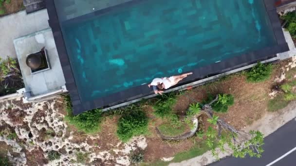 Pareja enamorada en un resort de lujo en vacaciones románticas de verano. Personas que se relajan juntas en la piscina de borde, disfrutando de la hermosa puesta de sol Vista al mar. Felices amantes en viaje de luna de miel. Relación — Vídeo de stock