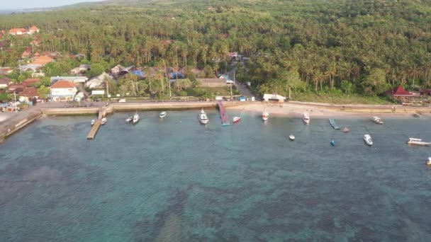 熱帯島の港を持つ小さな都市の航空写真、背景の休暇、旅行、日没4kの山々と日の出の小さな町でボートと海と日没 — ストック動画