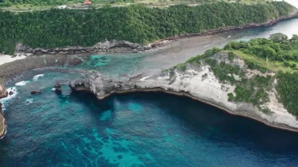 Вид з повітря на зеленому тропічному узбережжі острова Нуса-Пеніда, Atuh Beach, Балі, Індонезія. чіткі блакитні Океанські хвилі котяться до пляжу. 4K — стокове відео