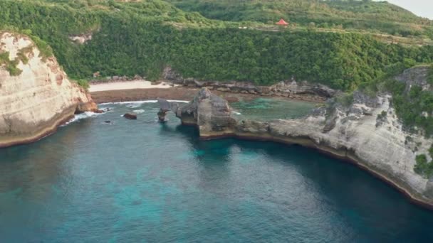 Vista aérea da costa tropical verde da ilha de Nusa Penida, praia Atuh, Bali, Indonésia.Ondas oceânicas azuis claras rolando para a praia. 4K — Vídeo de Stock