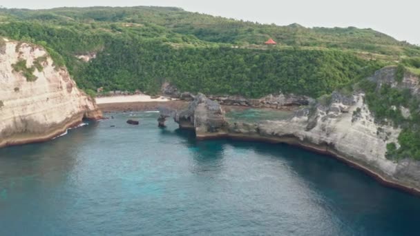 Flygfoto över den gröna tropiska kusten på ön Nusa Penida, Atuh Beach, Bali, Indonesien. klarblå havsvågor rullande till stranden. 4K — Stockvideo