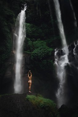 Şelale önünde rahatlatıcı bikini güzel genç kadın. Ekoturizm kavramı görüntü seyahat kız