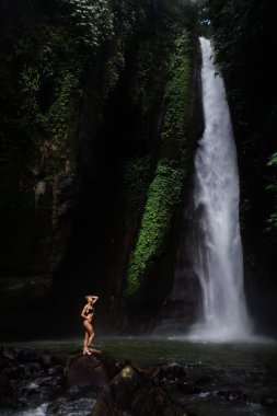 Şelale önünde rahatlatıcı bikini güzel genç kadın. Ekoturizm kavramı görüntü seyahat kız
