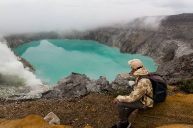 Adam turist Endonezya'da ada Java Üzerinde Ijen yanardağ sülfür gölü bakar. Sırt çantası ile Hiker adam üst dağda seyahat, seyahat konsepti