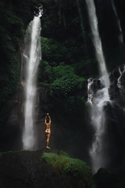 Şelale önünde rahatlatıcı bikini güzel genç kadın. Ekoturizm kavramı görüntü seyahat kız