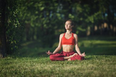 Dışarıda yoga yapan genç bir kadın. Kadın şehir parkında meditasyon yapıyor..