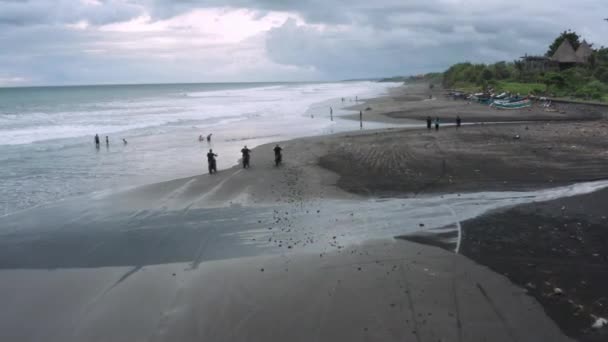 Tre stilig hipster män Rider modern Custom motorcykel Café racer på den svarta sandstranden nära havet. Äventyrsresor koncept. Surfplats med havsvågor. Antenn skott. 4K — Stockvideo