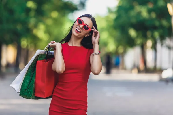 Alışverişe zevk alışveriş torbaları ile genç mutlu gülümseyen kadın portre. Pozitif duygular ve alışveriş günü konsepti. — Stok fotoğraf