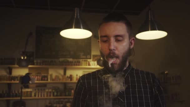 El hombre fuma un cigarrillo electrónico en la tienda de vapores. Movimiento lento . — Vídeo de stock