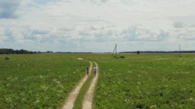 Oyuncu Çiftin El Ele Tutuşup Kırsal Yoldan Koşmasının Havadan Görünümü. Kamera önlerinde. 4k atış.