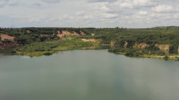 O casal está em pé num penhasco junto ao lago. Casal apaixonado abraçando contra o pano de fundo de belas vistas da natureza. Aéreo. 4K — Vídeo de Stock