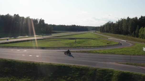 Homem de moto dirige através de um tempo de junção por do sol. Rastreamento aéreo disparado. 4K . — Vídeo de Stock