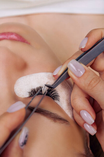 Eyelash Extension Procedure. Woman Eye with Long Blue Eyelashes. Ombre effect. Close up, selective focus.