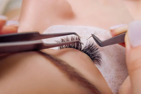 Wimpernverlängerungsverfahren. Frauenauge mit langen blauen Wimpern. Nahaufnahme, selektiver Fokus. — Stockfoto