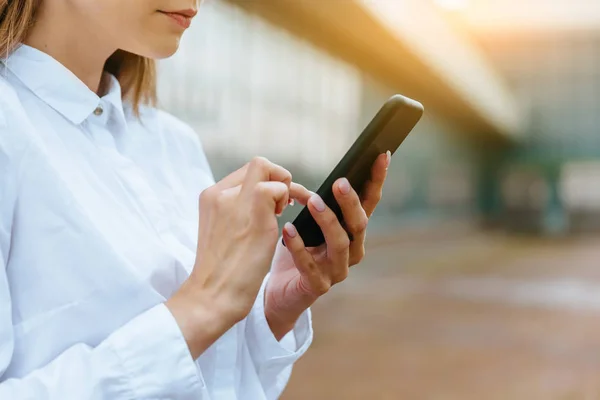 Cropped view of businesswoman using smartphone. Successful female entrepreneur checking email on smartphone. Female texting message. Office building Background. Technology internet and happy people — Stock Photo, Image