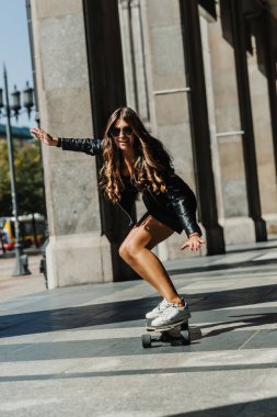 Güzel genç patenci kadın şehirde onu longboard sürme. Sokak kıyafetleri içinde şık kız uzun bir tahtaüzerinde sürmek. Kaykay, sokak fotoğrafı, yaşam tarzı, özgürlük, mutlu yüz konsepti.