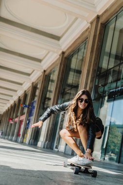 Güzel genç patenci kadın şehirde onu longboard sürme. Sokak kıyafetleri içinde şık kız uzun bir tahtaüzerinde sürmek. Kaykay, sokak fotoğrafı, yaşam tarzı, özgürlük, mutlu yüz konsepti.