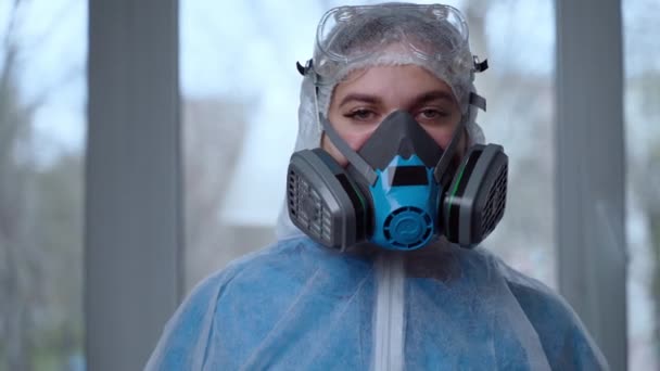 Retrato de mulher médico tecendo terno protetor durante a pandemia de coronavírus,. Médico feminino de fato de risco, máscara respiratória, luvas e óculos a preparar-se para o dia de trabalho na clínica ou no hospital — Vídeo de Stock