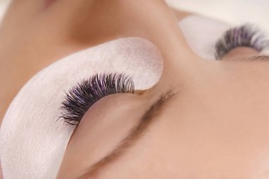 Kirpik uzatma prosedürü. Uzun kirpikli, pürüzsüz, sağlıklı ciltli güzel bir kadın gözü..