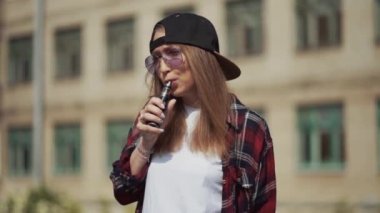 Siyah Vape Eckig giyen genç ve güzel bir hippi kadın. Kız Vape popüler ecig aleti, Vaping cihazı. E-sigaralı mutlu esmer vampir kız. Sigara içen kadın modelin elektronik sigarayla portresi.