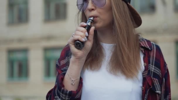 Κοντινό πλάνο όμορφη νεαρή hipster γυναίκα σε μαύρο καπέλο vape ecig. Κορίτσι vape δημοφιλές ecig gadget, vaping device.Happy μελαχρινή vaper κορίτσι με e-cig. Πορτρέτο του καπνιστή γυναικείο μοντέλο με ηλεκτρονικό τσιγάρο — Αρχείο Βίντεο