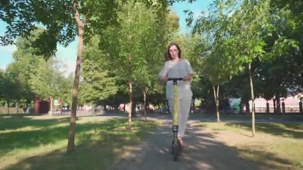 Vista frontal de la alegre adorable mujer mayor usando una scooter mientras monta en el parque. Mujer moderna, una nueva generación. Saludable señora jubilada alegre. Concepto de Inclusividad por Edad y Ecología — Vídeos de Stock