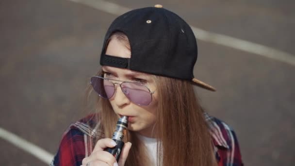 Close-up hübsche junge Hipster-Frau mit schwarzer Mütze vape ecig. Mädchen vape beliebte ecig Gadget, vaping device.Happy Brünette vaper Mädchen mit e-cig. Porträt eines weiblichen Rauchers mit elektronischer Zigarette — Stockvideo