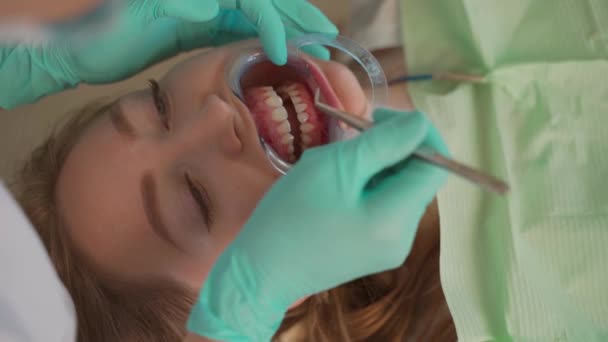 Dokter gigi membuat gigi profesional membersihkan pasien muda perempuan di kantor gigi. Kebersihan mulut dan profilaksis — Stok Video