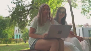 Genç bir kadın, emekli annesine laptopuyla parkta otururken yardım ediyor. Yaş Kapsayıcılığı kavramı