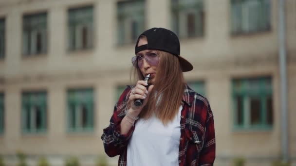 かなり若いヒップスター女性黒キャップvape ecigで。女の子は人気のecigガジェットを回避します,蒸気装置.電子タバコと喫煙者女性モデルの肖像 — ストック動画