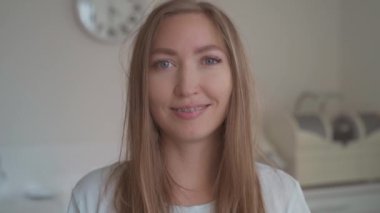 Diş teli takan gülümseyen kadın portresi. Diş sağlığı muayenehanesinin arka planında gülümseyen mutlu genç kadın kameraya bakıyor..