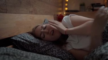 Yatak odasında öksüren genç bir kadın. Grip hastası bir kadın, yatakta kovid 19 semptomları var. Evde hapşıran, sakso çeken, kağıt mendille burnunu silen hasta bir kız. Alerji, virüs salgını, salgın,
