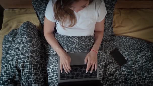 Schöne attraktive junge Frau, die mit Laptop auf dem Bett sitzt und am Computer-Laptop arbeitet, um soziale Medien zu nutzen und online einzukaufen, entspannen Sie sich zu Hause im gemütlichen Schlafzimmer. Arbeit von zu Hause aus — Stockvideo