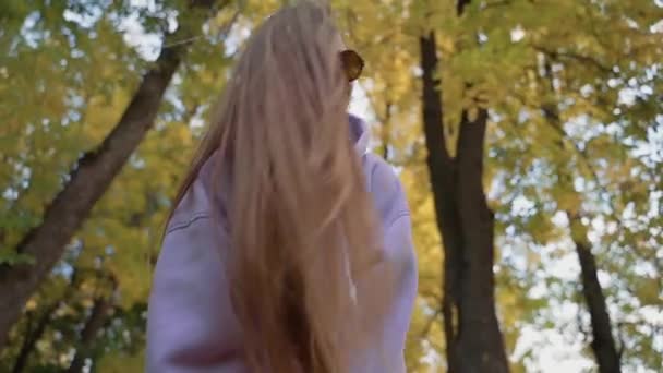 Portrait of Beautyful woman wearing pink hoodie with healthy Long Hair in forest. Happy female smiling and having fun in the park at sunny autumn day. Nature. slow motion. — Stock Video