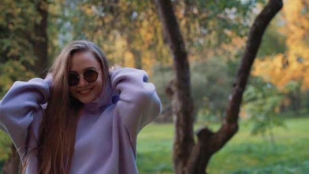 Portrait of Beautyful woman wearing pink hoodie with healthy Long Hair in forest. Happy female smiling and laughing in Autumn in sunny fall park outdoor. Nature. slow motion. — Stock Video