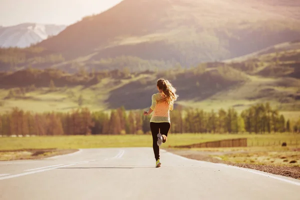 Κορίτσι τρέχει sunset road στα βουνά — Φωτογραφία Αρχείου