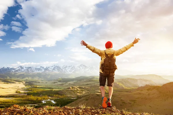 Glad turist man lyfte vapen mot solnedgången berg — Stockfoto