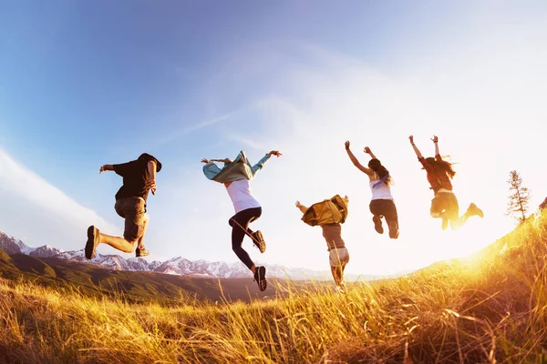 Grupo amigos felizes corre e salta montanhas por do sol — Fotografia de Stock