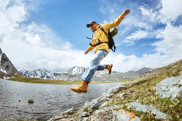 Wandelaar springen uit grote rots tegen bergen lake — Stockfoto