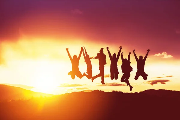 Amigos felizes silhuetas salta por do sol — Fotografia de Stock