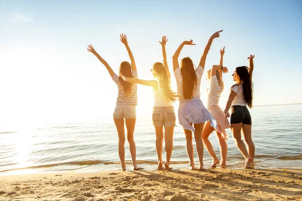 Ragazze felici con braccia alzate spiaggia tramonto — Foto Stock