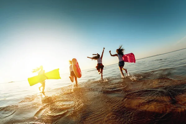 Quatro meninas felizes corre para o pôr do sol lago — Fotografia de Stock