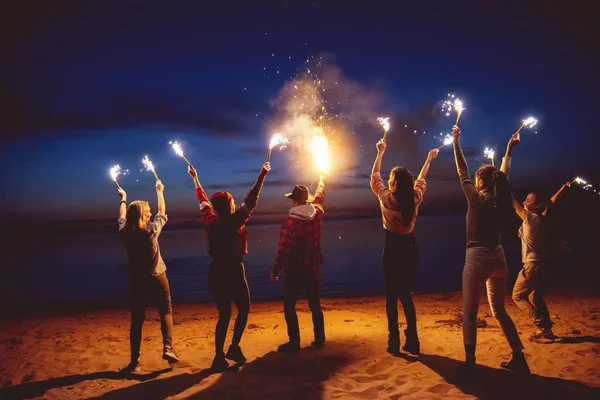 Gruppo amici crepuscolo segnale fuoco spiaggia — Foto Stock