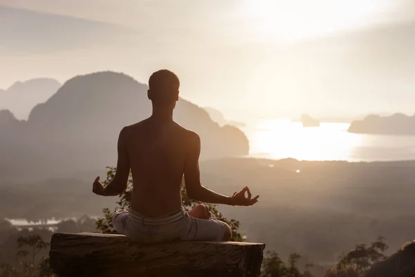 Man zit in yoga houding bij zonsopgang tegen zee — Stockfoto