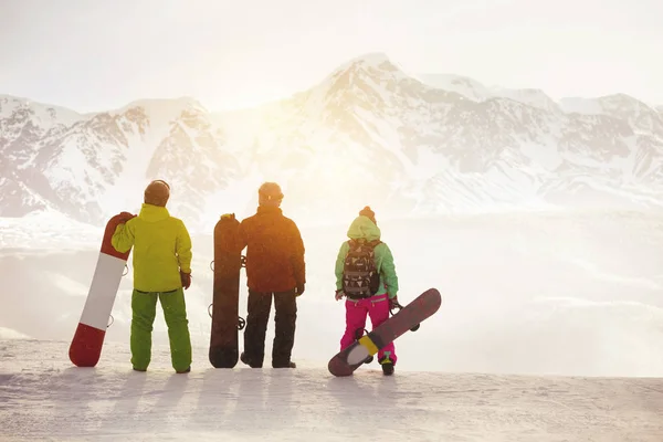 Tres snowboarders se alzan contra montañas — Foto de Stock