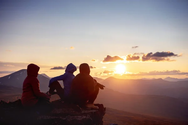 三位朋友坐在山顶上的日落景色 — 图库照片
