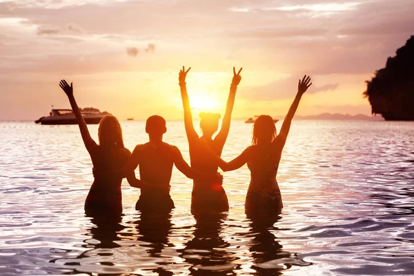 Quatro amigos felizes que encontram a praia do mar do por do sol — Fotografia de Stock