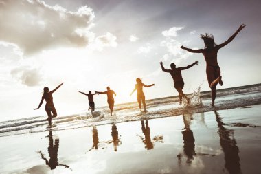 Grup mutlu genç insanlar atlama beach çalıştırmak